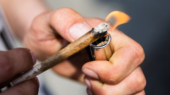 Ein Mann zündet einen Joint mit Medizinalcannabis an.