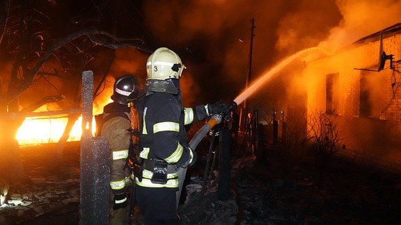 Feuerwehrleute löschen ein Feuer nach einem russischen Angriff auf ein Wohnviertel in Charkiw, Ukraine.