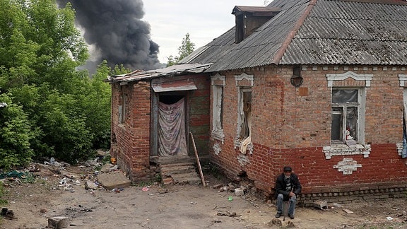 Nach dem Beschuss durch russische Truppen steigt hinter einem Haus eine Rauchsäule auf. 
