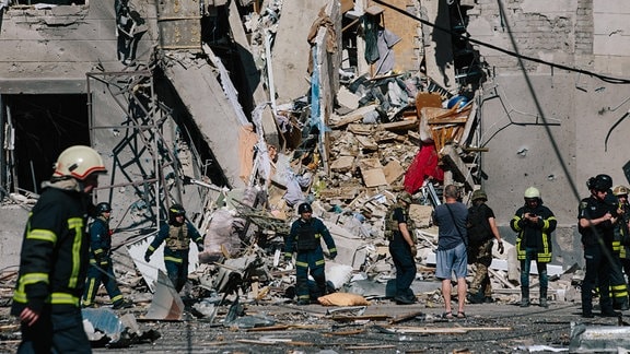 Einsatzkräfte vor einem zerstörten Haus.