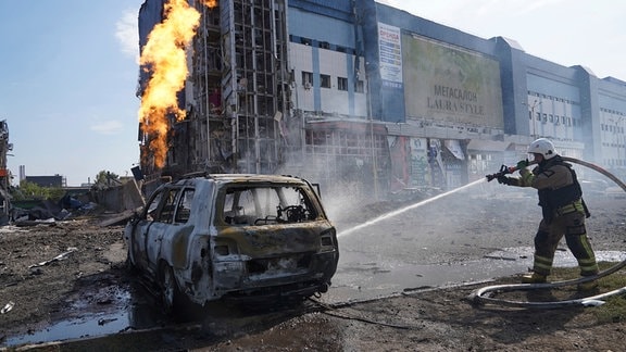 Ein ukrainischer Feuerwehrmann löscht ein ausgebranntes Fahrzeug nach russischem Angriff auf Charkiw (1. September)