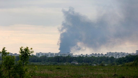 Nach dem Beschuss durch russische Truppen steigt eine Rauchsäule hinter Wohnhäusern auf.