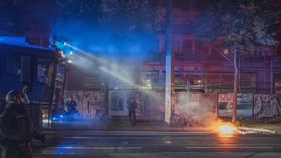 Polizisten und Einsatzfahrzeug in der Nähe einer Brandstelle auf einer Straße