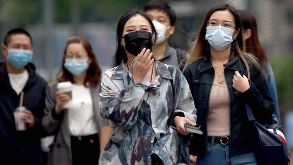 Chinesische Bürger während des Einkaufbummels mit Masken.