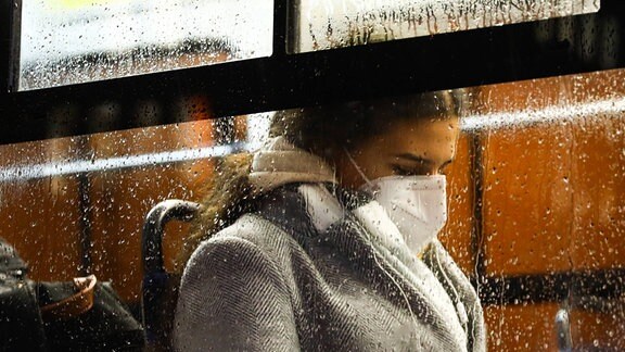Eine Passagierin in einem öffentlichen Bus trägt eine Gesichtsmaske.