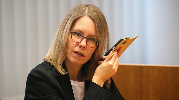 Anne Brorhilker, Oberstaatsanwältin hört im Landgericht in ihr Smartphone.