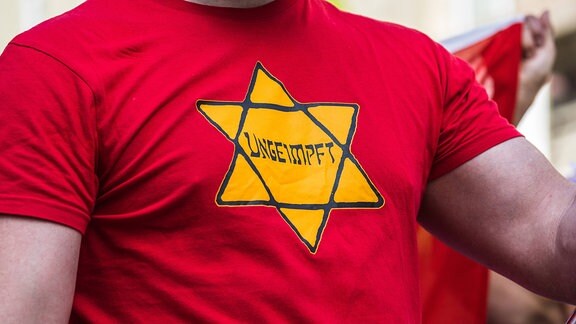 Demonstrant trägt 2021 T-Shirt mit Davidstern und Aufschrift "UNGEIMPFT"