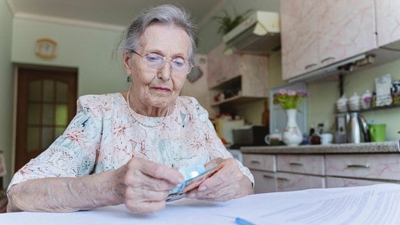 Eine ältere Frau, die zu Hause Geld zählt.