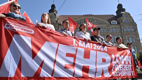 Teilnehmende einer Demonstration der IG Metall und des DGB Hessen-Thüringen zum Tag der Arbeit stehen mit Fahnen und Bannern auf dem Erfurter Anger. 