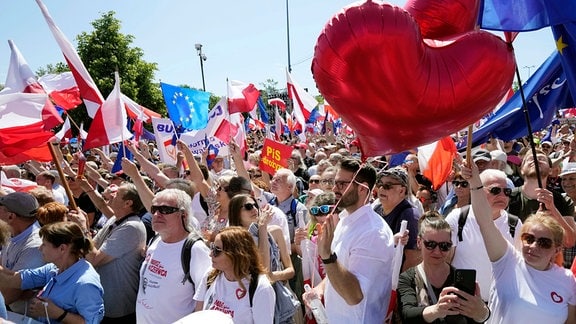 Menschen halten Luftballons und Fahnen, während sie an einem Protest gegen die Politik der PiS-Regierung teilnehmen