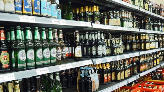Bierflaschen verschiedener Marken stehen in einem Supermarkt.