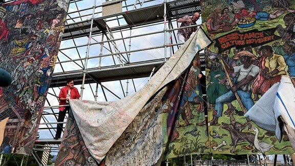 Documenta-Mitarbeiter bauen das umstrittene Großbanner "People's Justice" des indonesischen Künstlerkollektivs Taring Padi auf dem Friedrichsplatz in Kassel ab. 