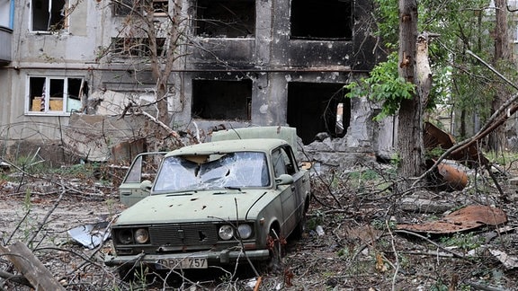 Eine Ansicht zeigt ein beschädigtes Auto neben einem Wohnhaus, das im Zuge der russischen Militäroperation in der Ukraine zerstört wurde, in der befreiten Stadt Krasnogorovka.