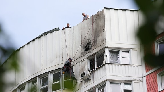 Menschen untersuchen ein beschädigtes Gebäude