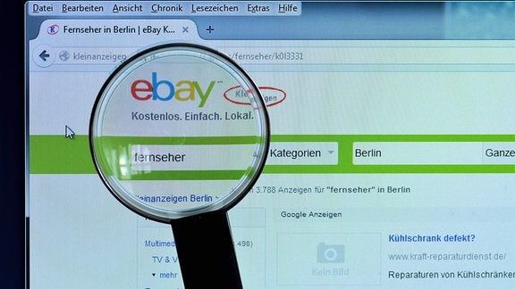 ebay Kleinanzeigen auf einem Bildschirm, davor eine Lupe.