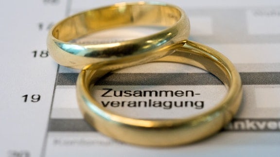 Goldene Eheringe liegen auf Formularen für die Steuererklärung.
