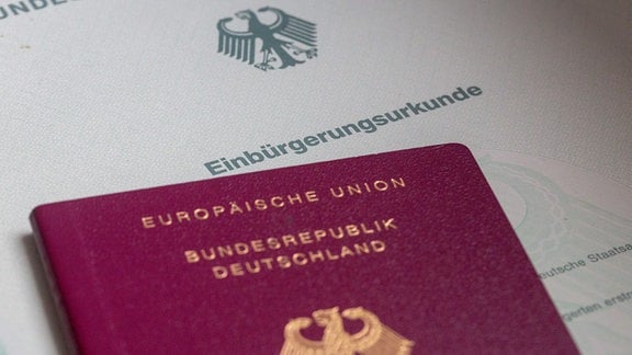 Eine Einbürgerungsurkunde der Bundesrepublik Deutschland und ein deutscher Reisepass liegen übereinander.