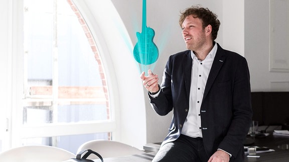 Hans Elstner, Gründer des Jenaer Start-ups "Rooom" mit einer virtuellen E-Gitarre in einer Hand.