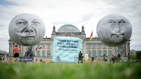 Große Ballone mit den Konterfeis des Bundeskanzlers (l) und des Finantministers schweben vor dem Reichstagsgebäude. 
