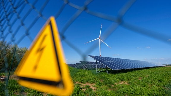 Ein Solarpark und eine Windkraftanlage stehen unmittelbar nebeneinander.