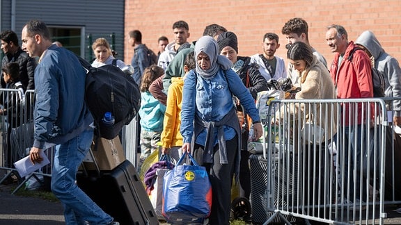 Flüchtlinge gehen in der hessischen Erstaufnahmeeinrichtung (HEAE) in Gießen zu einem wartenden Bus. 