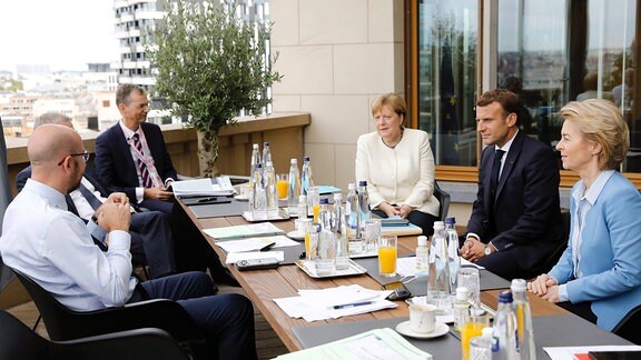 Mehrere Staatsführer sitzen bei einem Gespräch an einem Tisch.