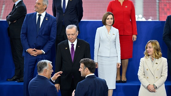 Ungarns Ministerpräsident Viktor Orban (vorne,l-r) spricht mit dem französischen Präsidenten Emmanuel Macron und dem türkischen Präsidenten Recep Tayyip Erdogan (M) während der Aufstellung zum Gruppenfoto beim Gipfel der Europäischen Politischen Gemeinschaft (EPG).