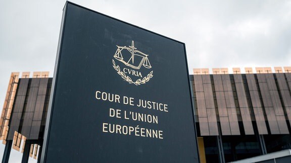 Schild mit der Aufschrift "Cour de Justice de l'Union Europeene" vor einem Gebäude des Europäischen Gerichtshofs (EuGH) in Luxemburg. 