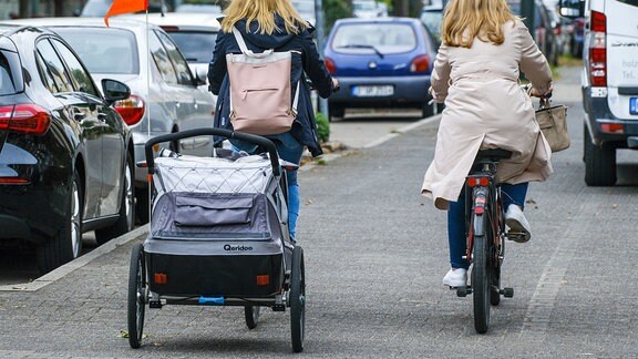 Fahrrad mit Kinderwagen-Anhänger auf Radweg.