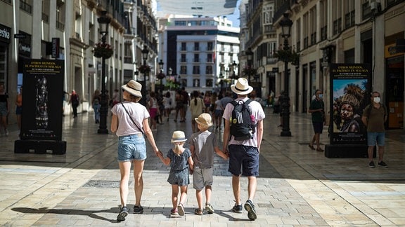 Eine Familie von Touristen spaziert die Straße Marques de Larios entlang, als sie inmitten der Corona-Pandemie die Innenstadt besucht.