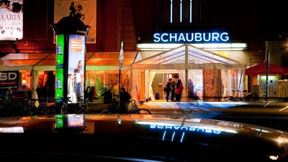 Ein hell erleuchtetes Gebäude, an der Fassade eine Leuchtreklame: "Schauburg".