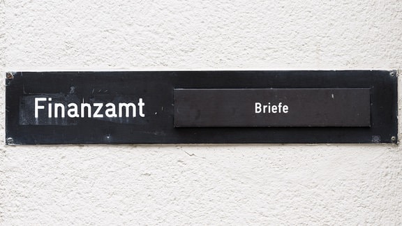 Der Schriftzug 'Finanzamt' steht auf einem Schild neben einem Briefkasten.
