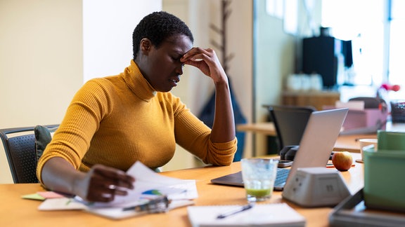 Frustrierte Geschäftsfrau sitzt am Schreibtisch im Büro