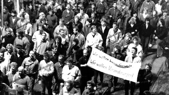 Das Archivbild vom 09.10.1989 zeigt eine Gruppe von Demonstranten mit einem Transparent, auf dem "Wir wollen keine Gewalt! Wir wollen Veränderungen!" zu lesen ist, bei der Montagsdemonstration in Leipzig. 