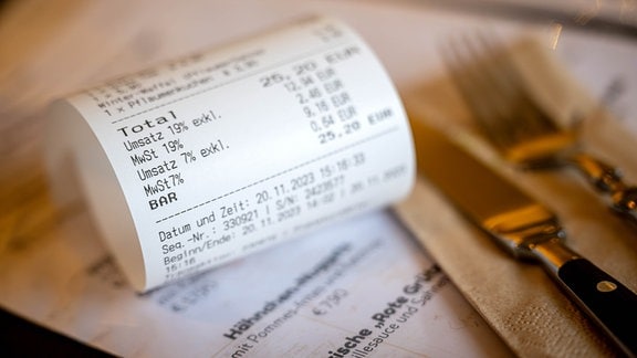 Eine Rechnung mit Umsatzsteuer und Mehrwertsteuer liegt auf der Speisekarte eines Restaurants