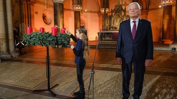 Joachim Gauck, Bundespraesident a.D., und Emilie, 8 Jahre, die die erste Kerze am Adventskranz anzündet