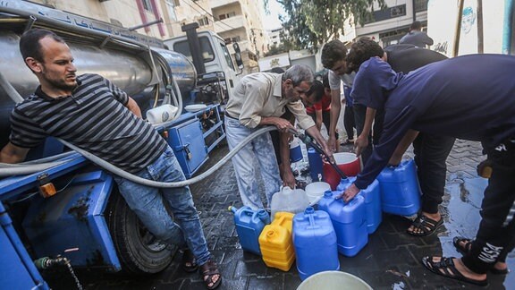 Palästinenser füllen Behälter mit Trinkwasser aus einem Wasserverteilungsfahrzeug auf.