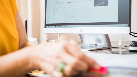  Eine Rentnerin sitzt an ihrem Schreibtisch schaut sich am PC Aktien-Charts an