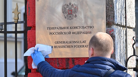 Ein Mitarbeiter reinigt das Schild des russischen Generalkonsulats.