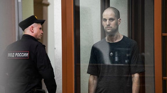 Der Wall Street Journal-Reporter Evan Gershkovich (r) hört sich das Urteil in einem Glaskäfig des Gerichtssaals im Justizpalast an.