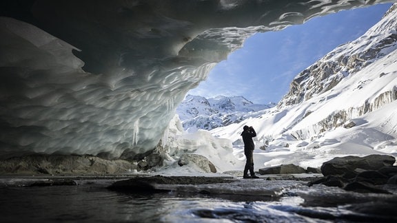 Ein Fotograf macht ein Bild in einer Gletscherhöhle am Morteratschgletscher. Der Morteratschgletscher ist ein Alpen-Gletscher m Kanton Graubünden .