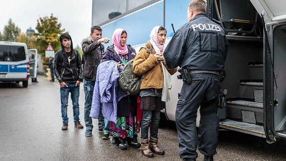 Migranten sprechen mit einem Polizisten nachdem sie über die Österreichische Grenze im Bundesgebiet angekommen sind. 2015