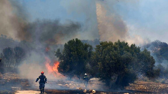 Feuerwehrleute versuchen einen Flächenbrand einzudämmen, der bereits den zweiten Tag in Folge brennt.