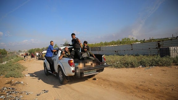 Militante Palästinenser fahren mit einem Pickup, auf dem möglicherweise eine deutsch-israelische Frau zu sehen ist, in den Gazastreifen zurück.