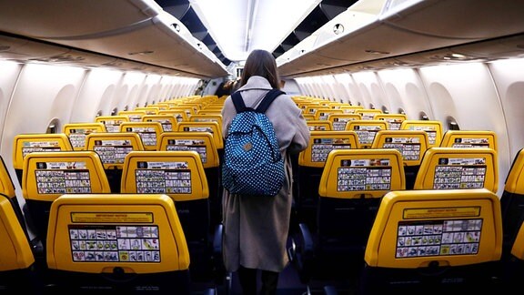 Passagierin mit blauem Rucksack in einem leeren Flugzeug