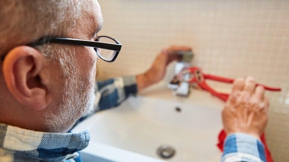 Handwerker Installateur oder Heimwerker repariert defekten Wasserhahn im Badezimmer