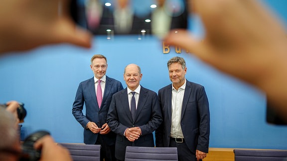 Bundeskanzler Olaf Scholz (SPD, M), Robert Habeck (r, Bündnis 90/Die Grünen), Bundesminister für Wirtschaft und Klimaschutz, und Christian Lindner (FDP), Bundesminister der Finanzen, nehmen an einer Pressekonferenz zum Haushaltsplan 2025 teil. 