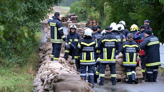 Feuerwehrleute während einer Besprechung neben einem Deich.