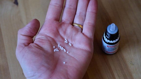 Homöopathische Kügelchen liegen in einer Hand. 