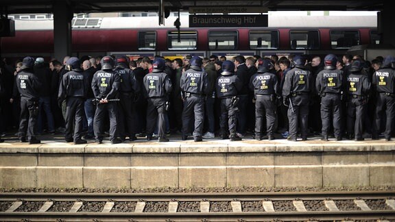 Polizeibeamte stehen auf dem Hauptbahnhof in Braunschweig (Niedersachsen) am Bahnsteig, um 700 ankommende Ultras und Hooligans zu empfangen.